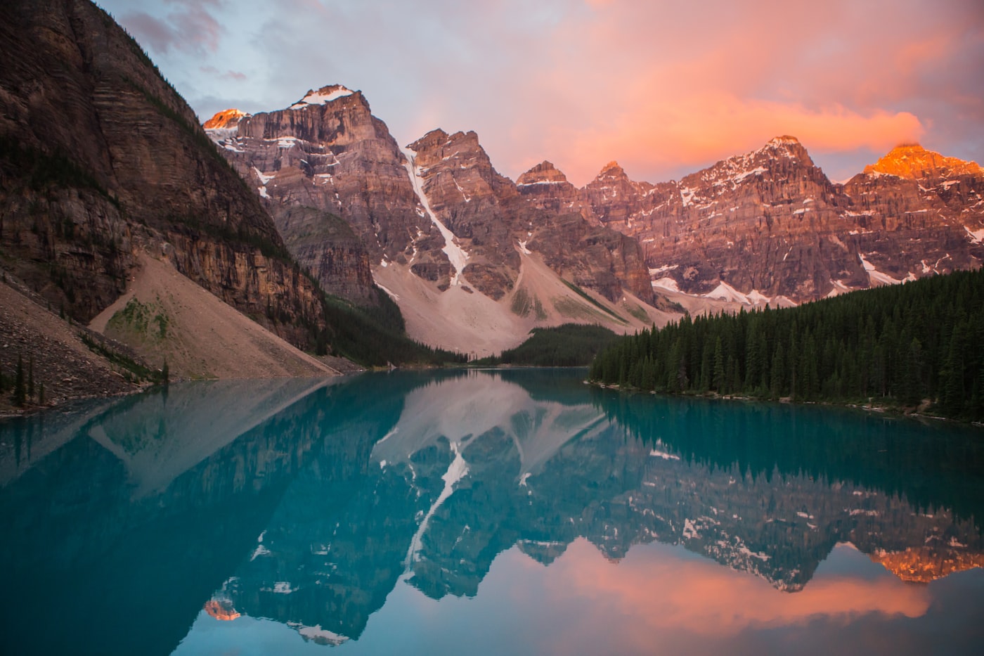 Misty turquoise alpine lake at sunrise with mountain peaks reflected on the still water
